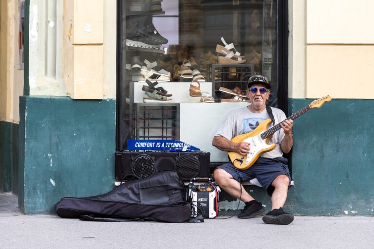 Musicista con chitarra e una piccola cassa amplificata su una via lastricata del centro