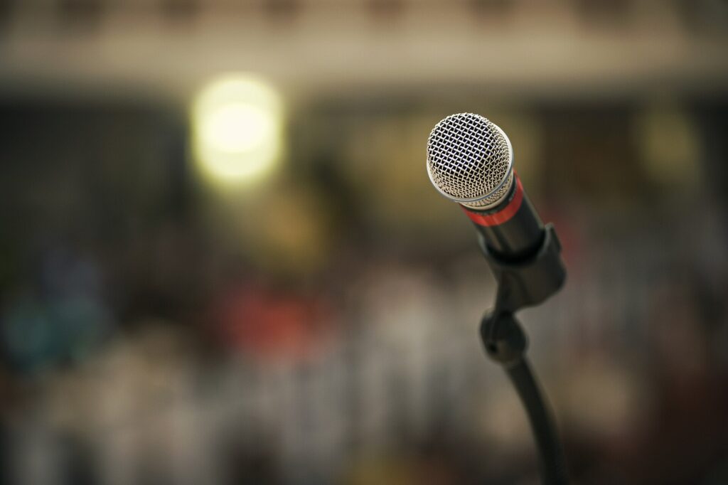 Microfono montato su un'asta al centro del palco con le luci abbassate alle spalle
