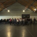 Sala prove spoglia con pavimento in legno e alcune sedie appoggiate lungo la parete