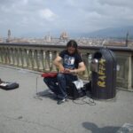 1920px-Street_musician_playing_piano_on_a_guitar_in_Florence