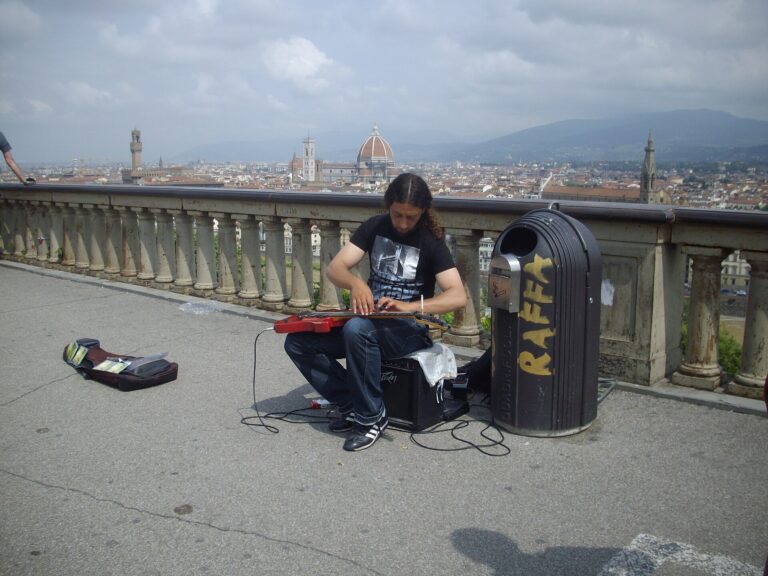 1920px-Street_musician_playing_piano_on_a_guitar_in_Florence