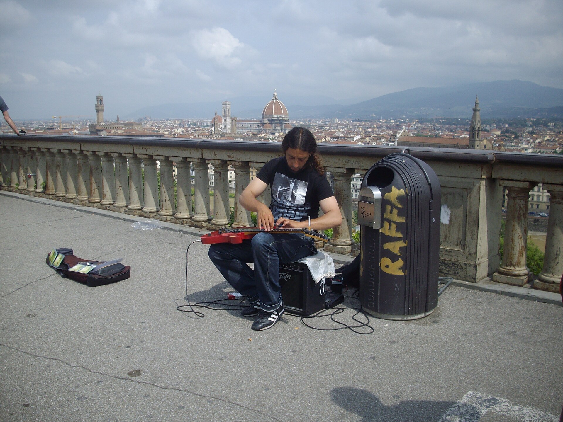 1920px-Street_musician_playing_piano_on_a_guitar_in_Florence