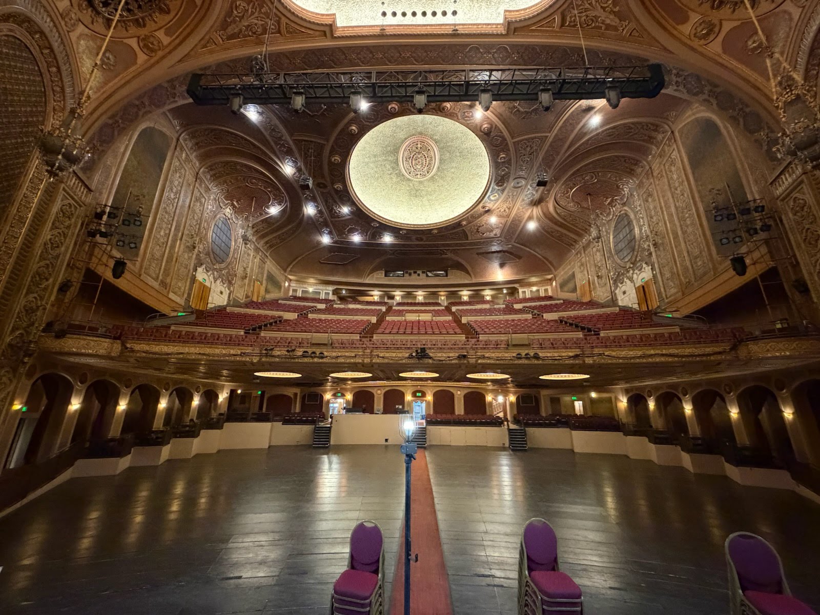 Platea di un teatro vuoto con file di poltrone rosse rivolte verso il palcoscenico