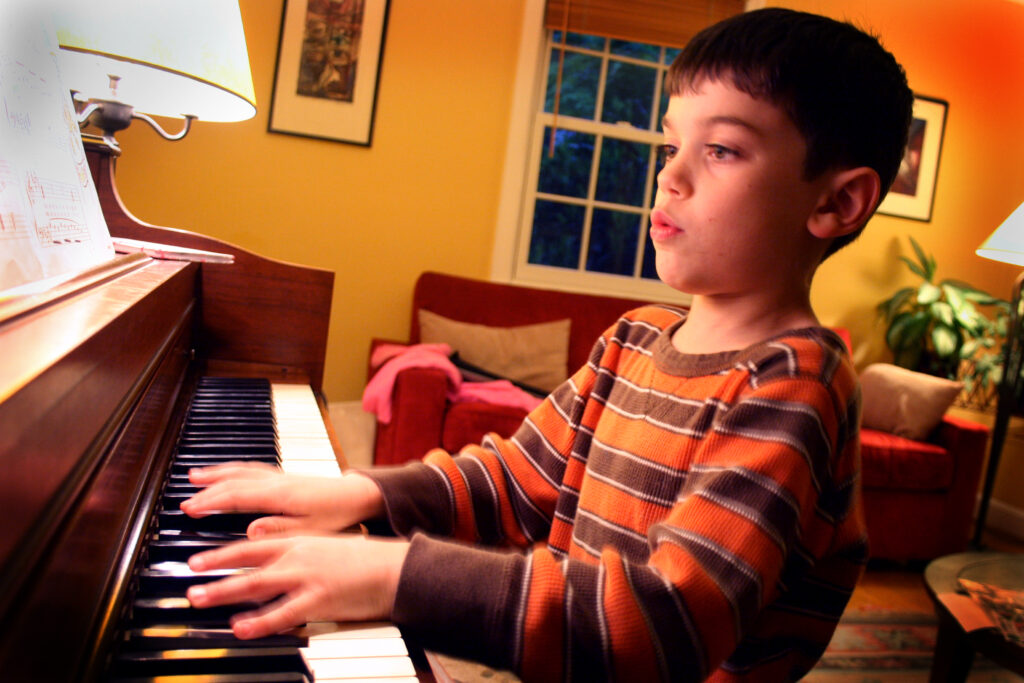 Pianoforte verticale in una stanza spoglia con una sedia e un leggio accanto