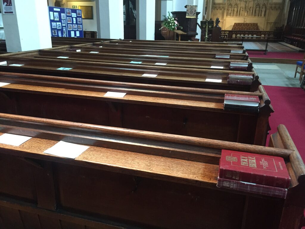 File di panche di legno vuote in una navata di chiesa poco illuminata