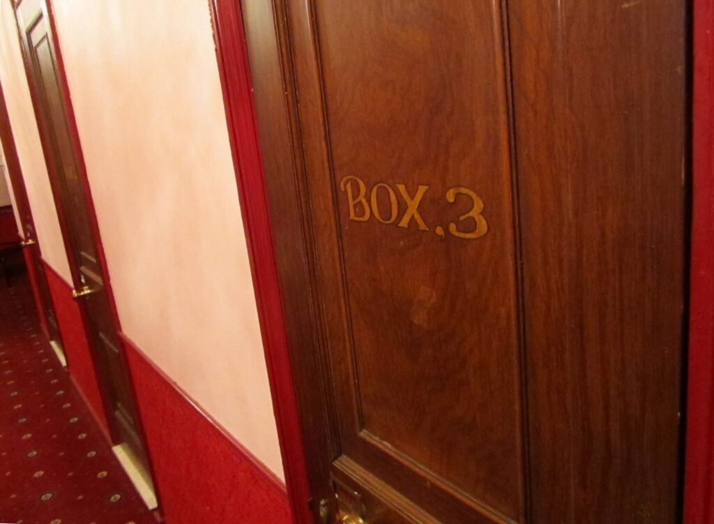 Palchi sovrapposti con parapetti decorati e tendaggi scuri lungo la parete laterale