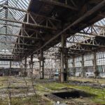 Grande capannone industriale con pareti in mattoni, capriate metalliche e pavimento in cemento