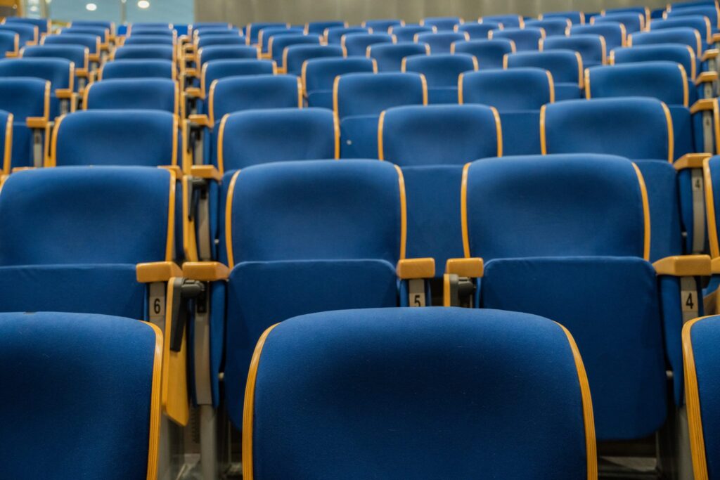 Sala da concerto vuota con palco illuminato e transenne davanti alla prima fila