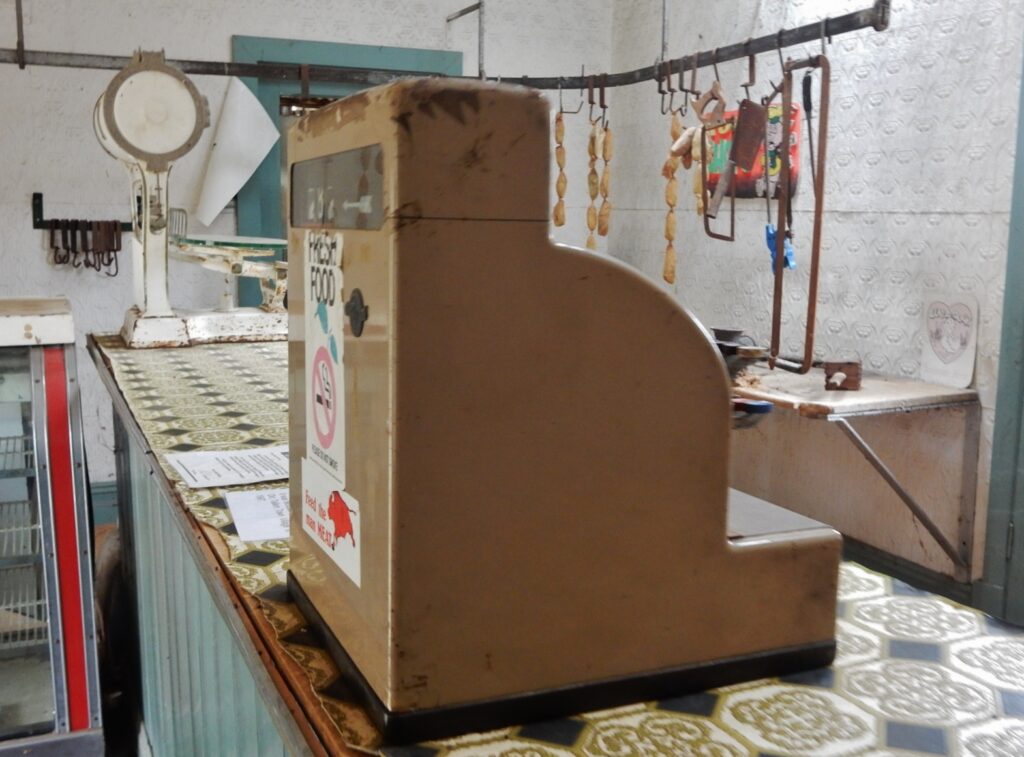 Registratore di cassa su un bancone di legno accanto a bicchieri e a una piccola lampada