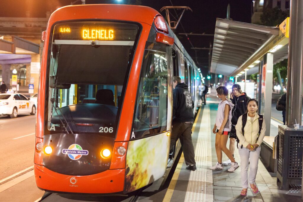 Fermata del tram illuminata di notte con le rotaie bagnate e nessuno in attesa